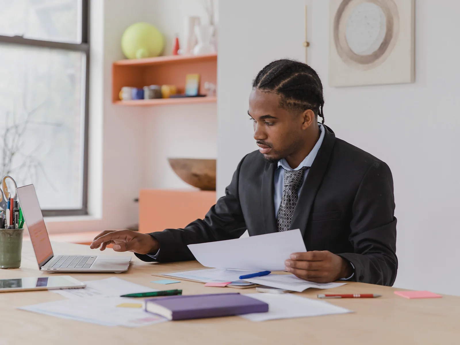 Advisor comparing a printed financial document with information on a laptop