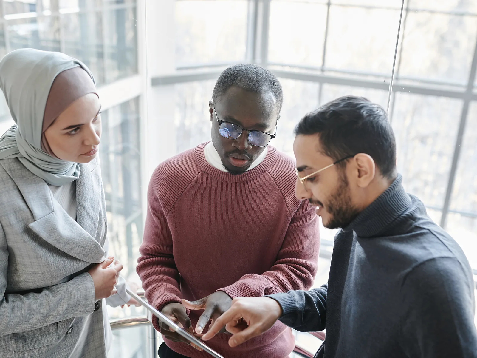 Three professionals reviewing information together on a tablet in a bright office